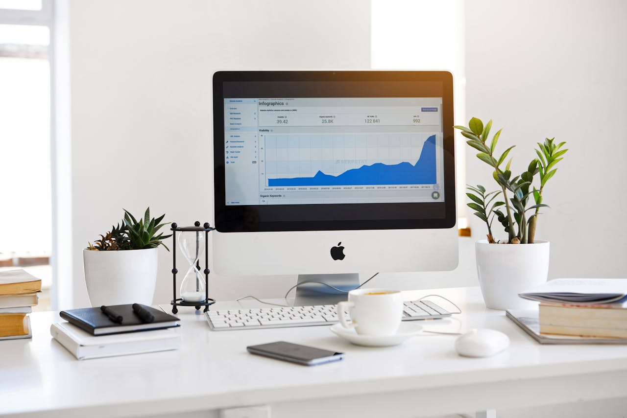 hero-img A clean, contemporary workspace featuring a desktop with analytics on the screen and plants for a fresh look.